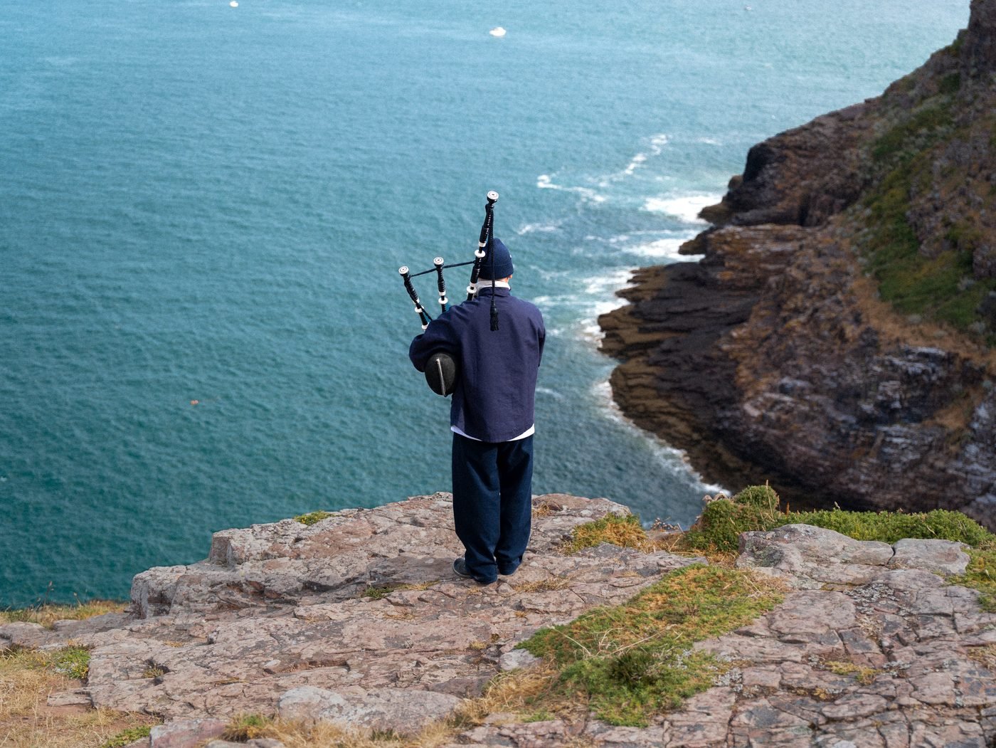Le sonneur de dos au bord de la falaise, face à la mer turquoise.