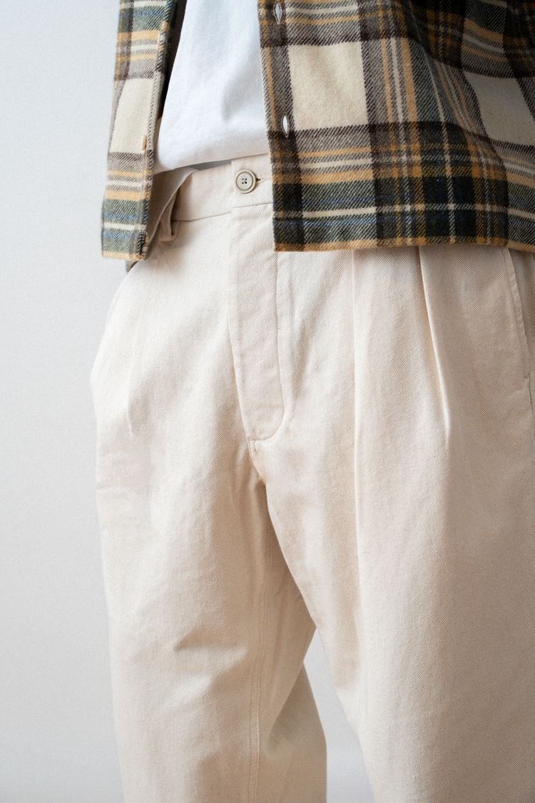 Détail du pantalon Marin écru porté avec une surchemise à carreaux.