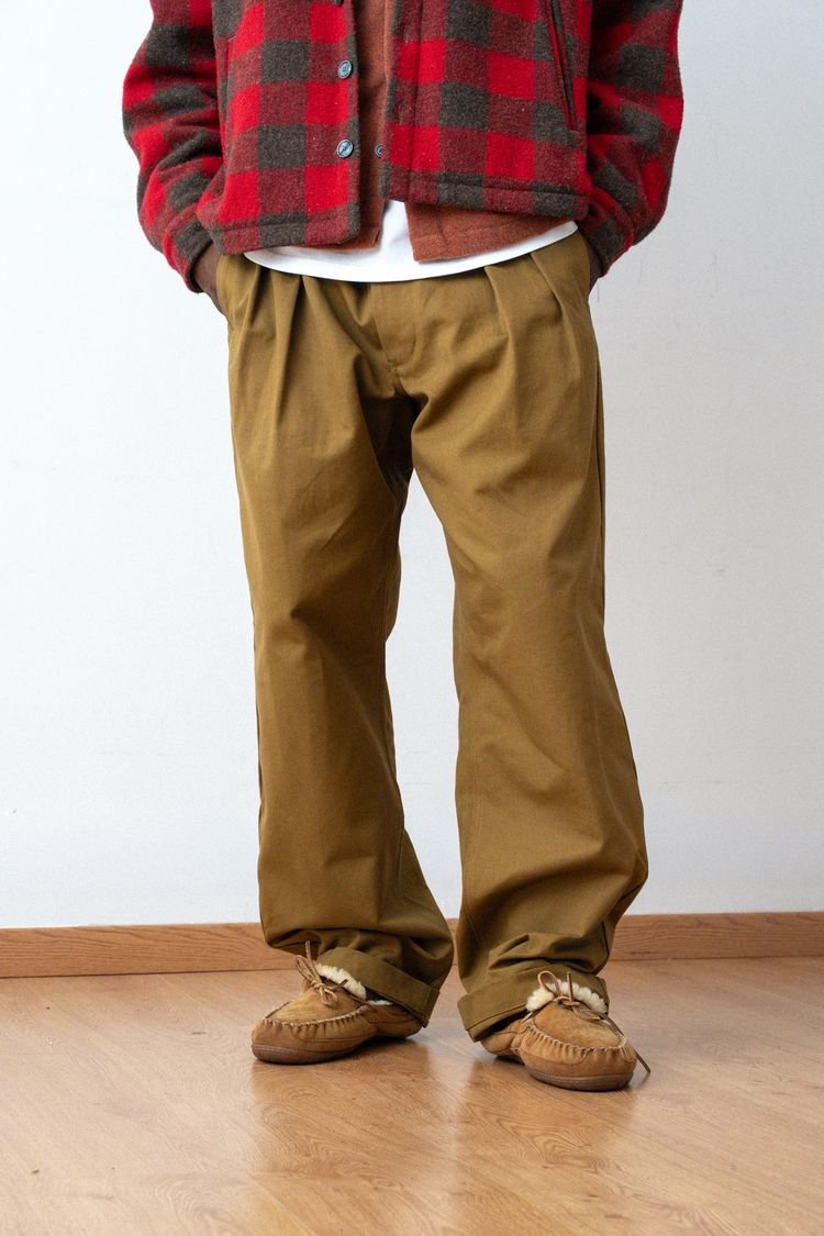 Pantalon Marin cognac porté avec une surchemise à carreaux rouges.