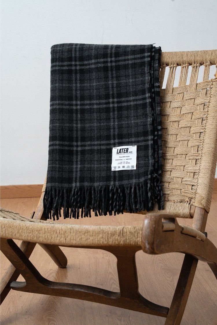 Plaid à carreaux gris et noirs posé sur une chaise en bois.