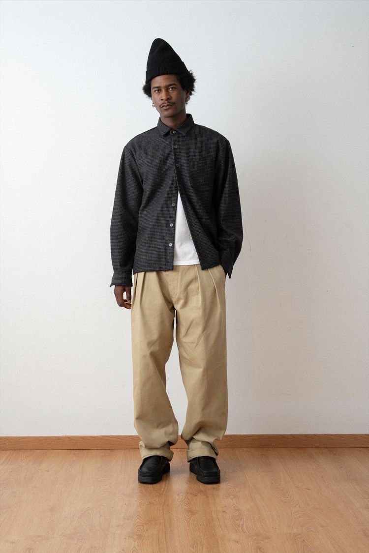 Surchemise épurée noire et pantalon beige, en pied.